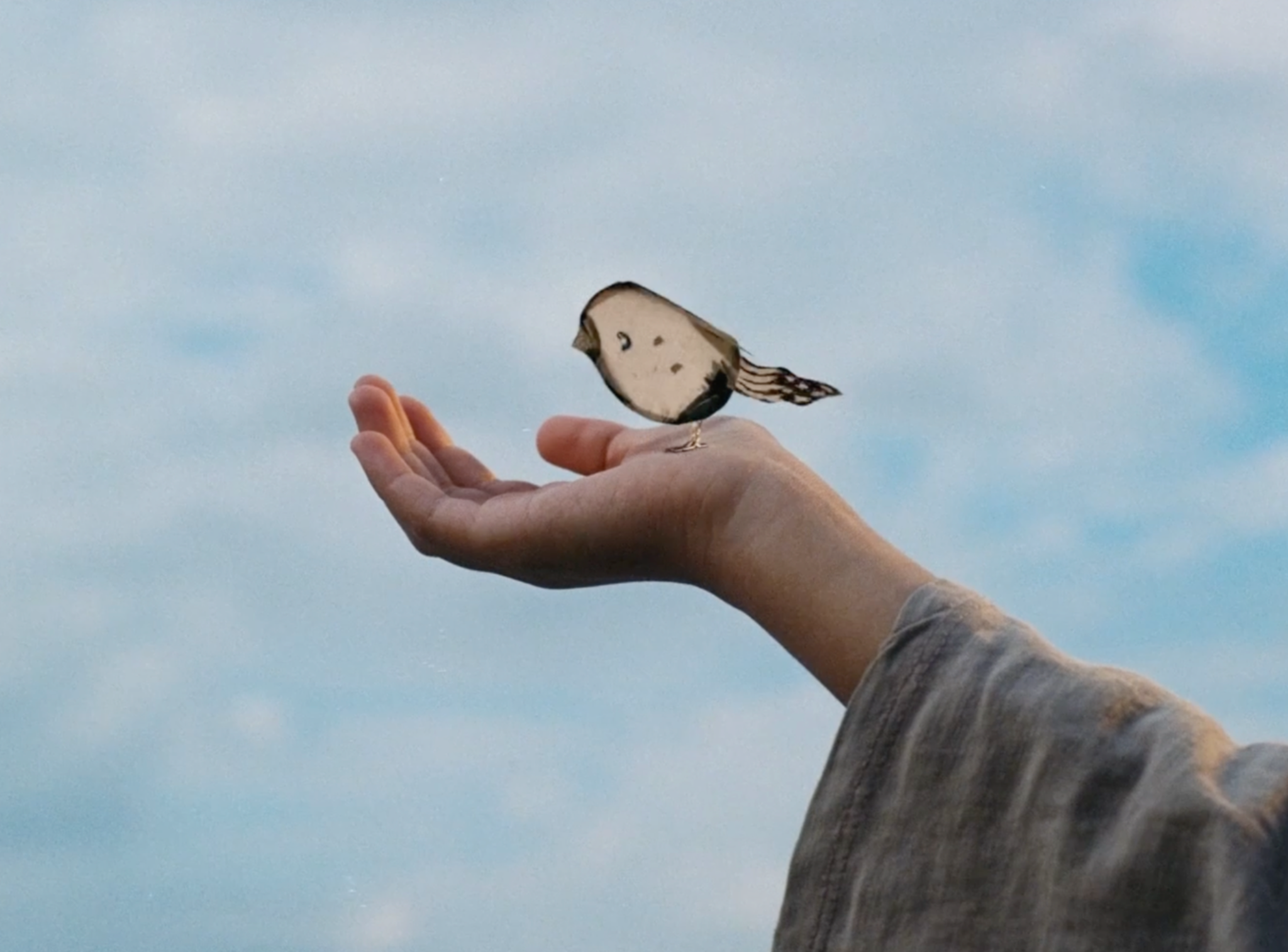 A hand holding an illustrated bird character
